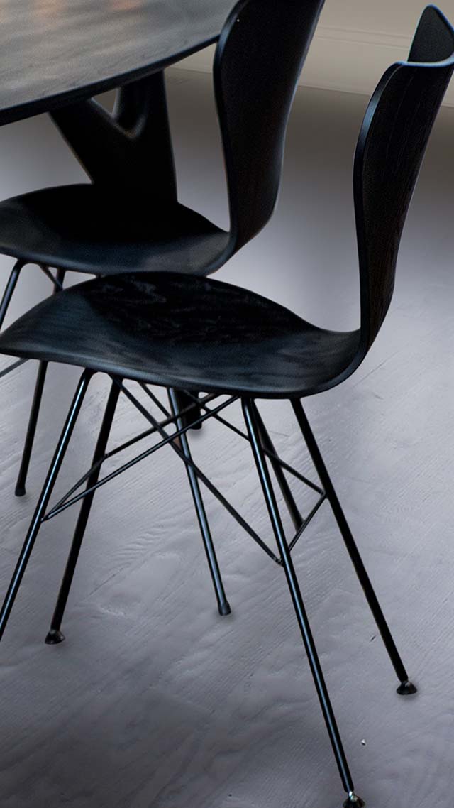 Rear view of the Reah chair in black, highlighting its curved wooden backrest and sleek, minimalist design